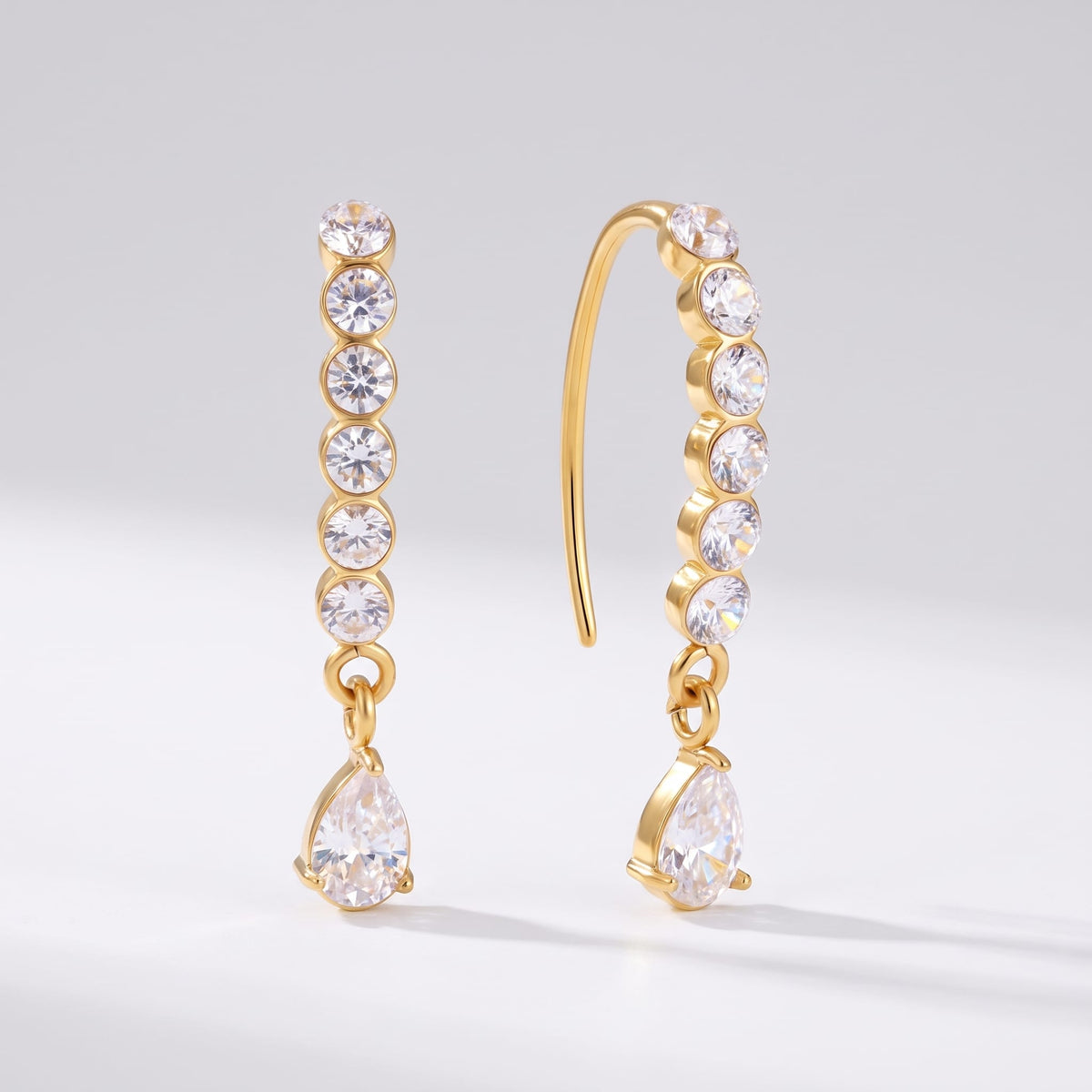 Sol(ne crystal drop gold earrings on a plain white surface displaying hook wire and zircon drops