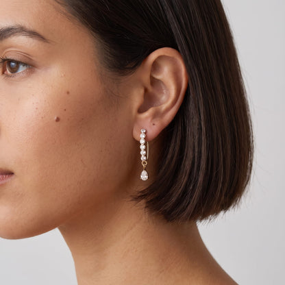 Woman wearing the Sol(ne crystal drop gold earrings on the ear, showing a profile view with dark short hair