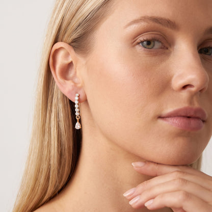 Woman wearing the Sol(ne crystal drop gold earrings on the ear, resting her chin on her hand