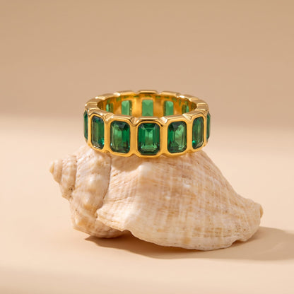 Sophie green baguette gold ring on a seashell against a beige background