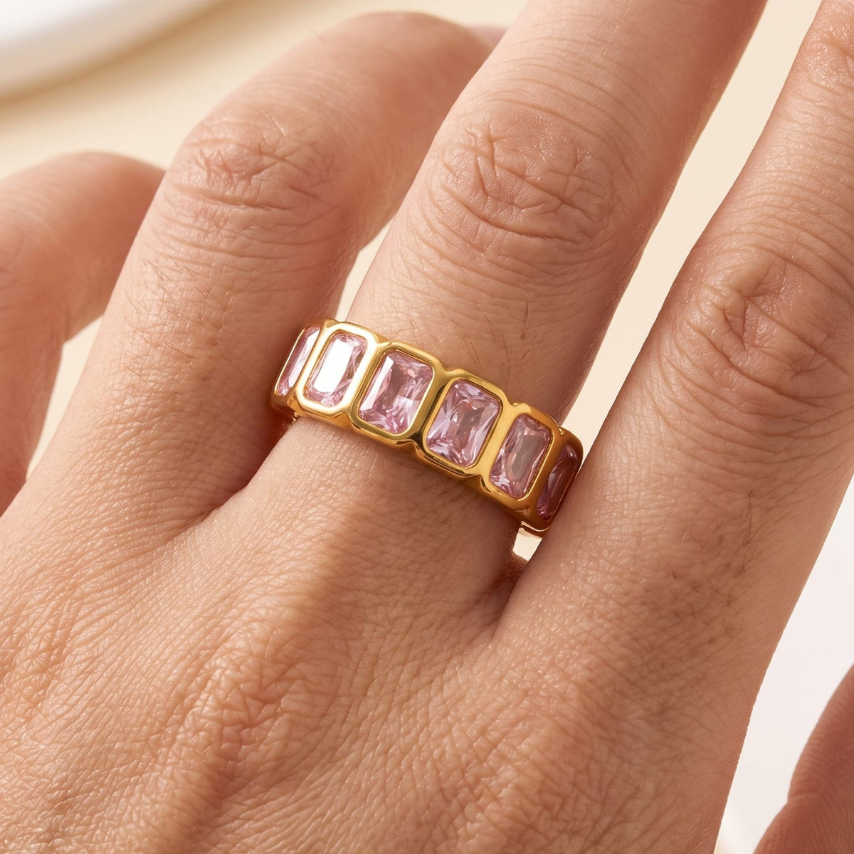 Woman wearing the Sophie pink baguette gold ring on the hand, featuring pink crystals