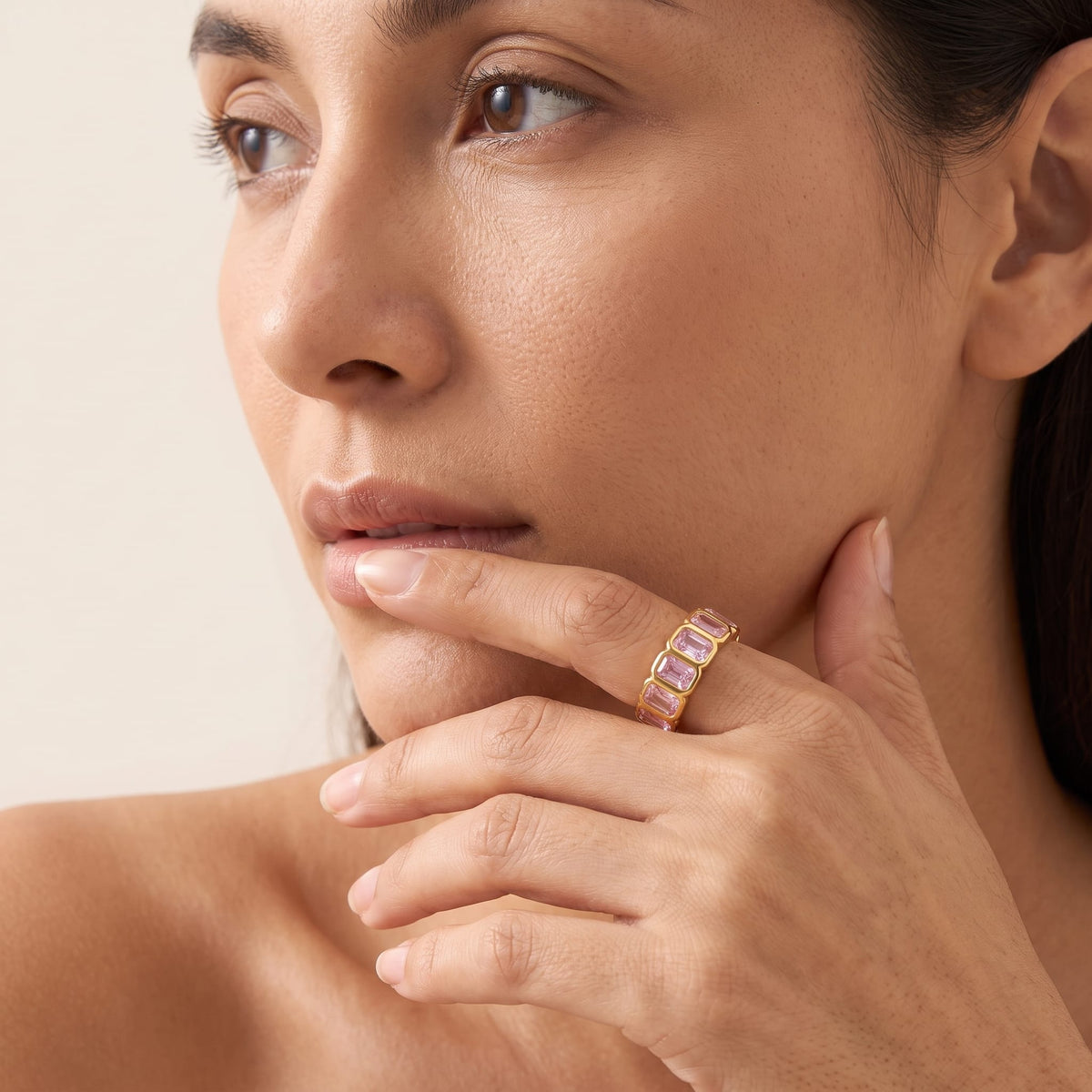 Woman wearing the Sophie pink baguette gold ring on the hand while looking away