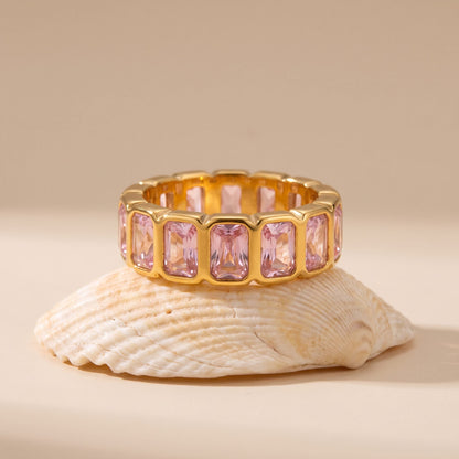 Sophie pink baguette gold ring on a white seashell against a beige background