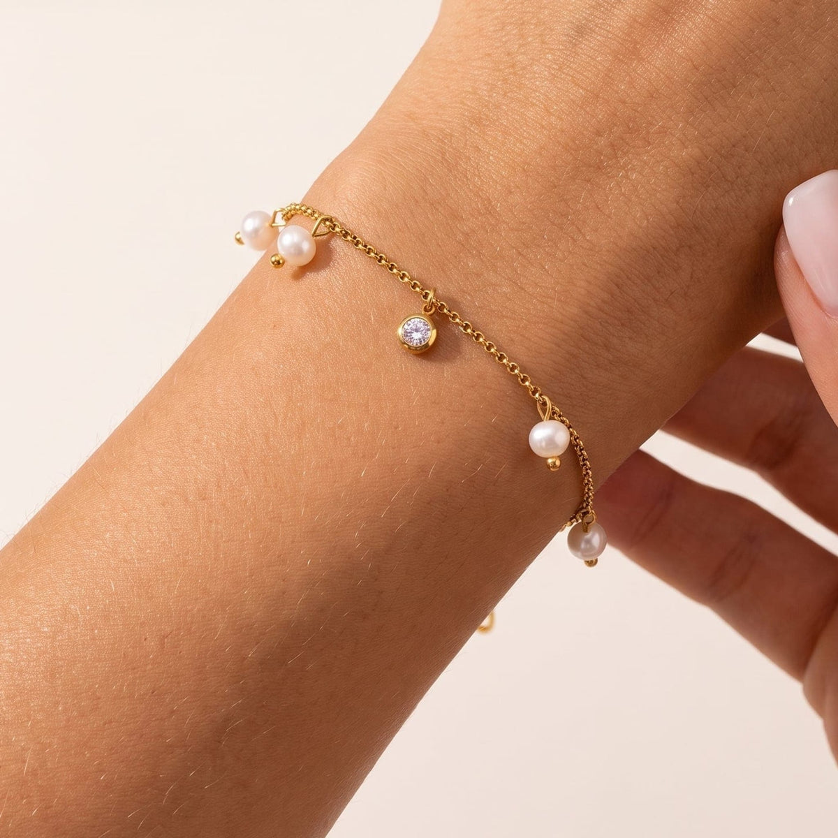 Woman wearing the Teresa pearl charm gold bracelet on the wrist