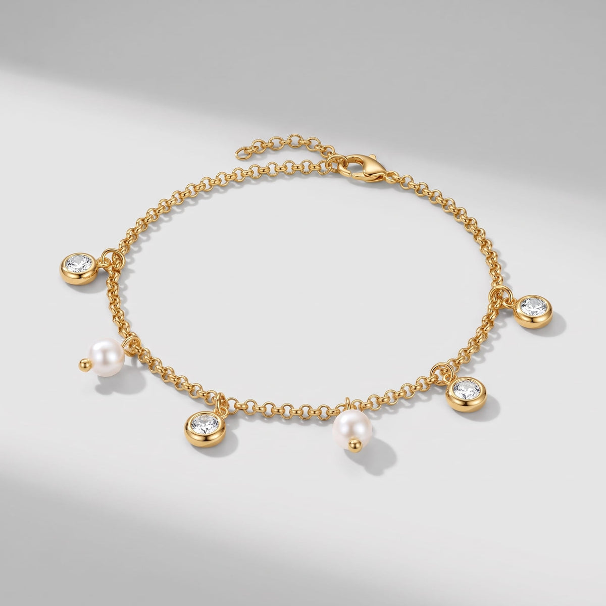 Teresa pearl charm gold bracelet on a plain white surface casting soft diagonal shadows