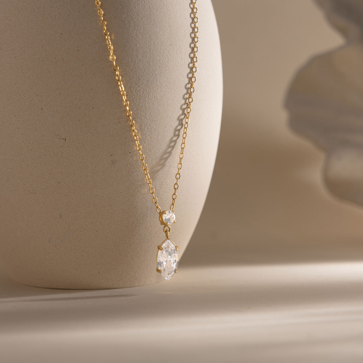Valentina marquise drop necklace hanging against a stone vase in warm side light