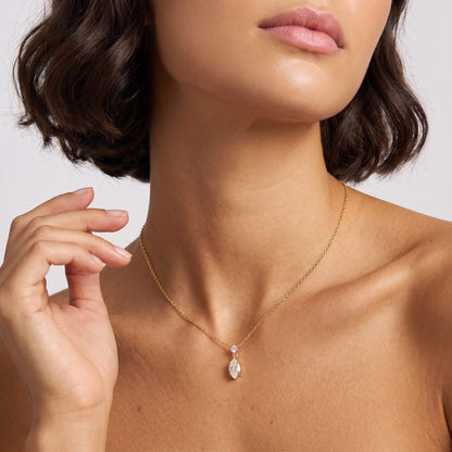 Woman wearing the Valentina marquise drop gold necklace at the throat with hand raised near neck