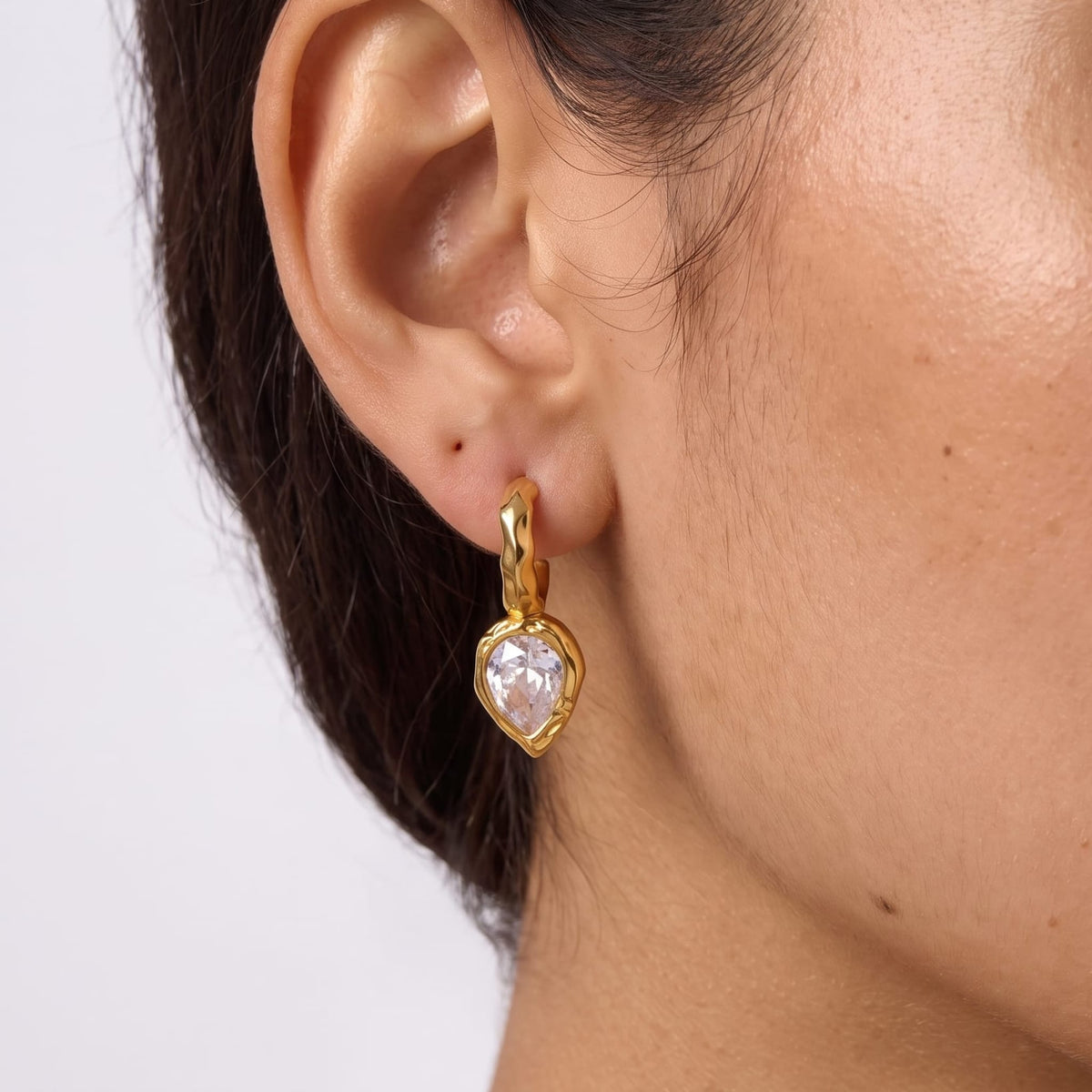 Woman wearing the Victoire hammered teardrop gold earrings on her ear close up