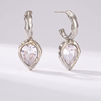 Victoire hammered teardrop silver earrings on a plain light grey surface