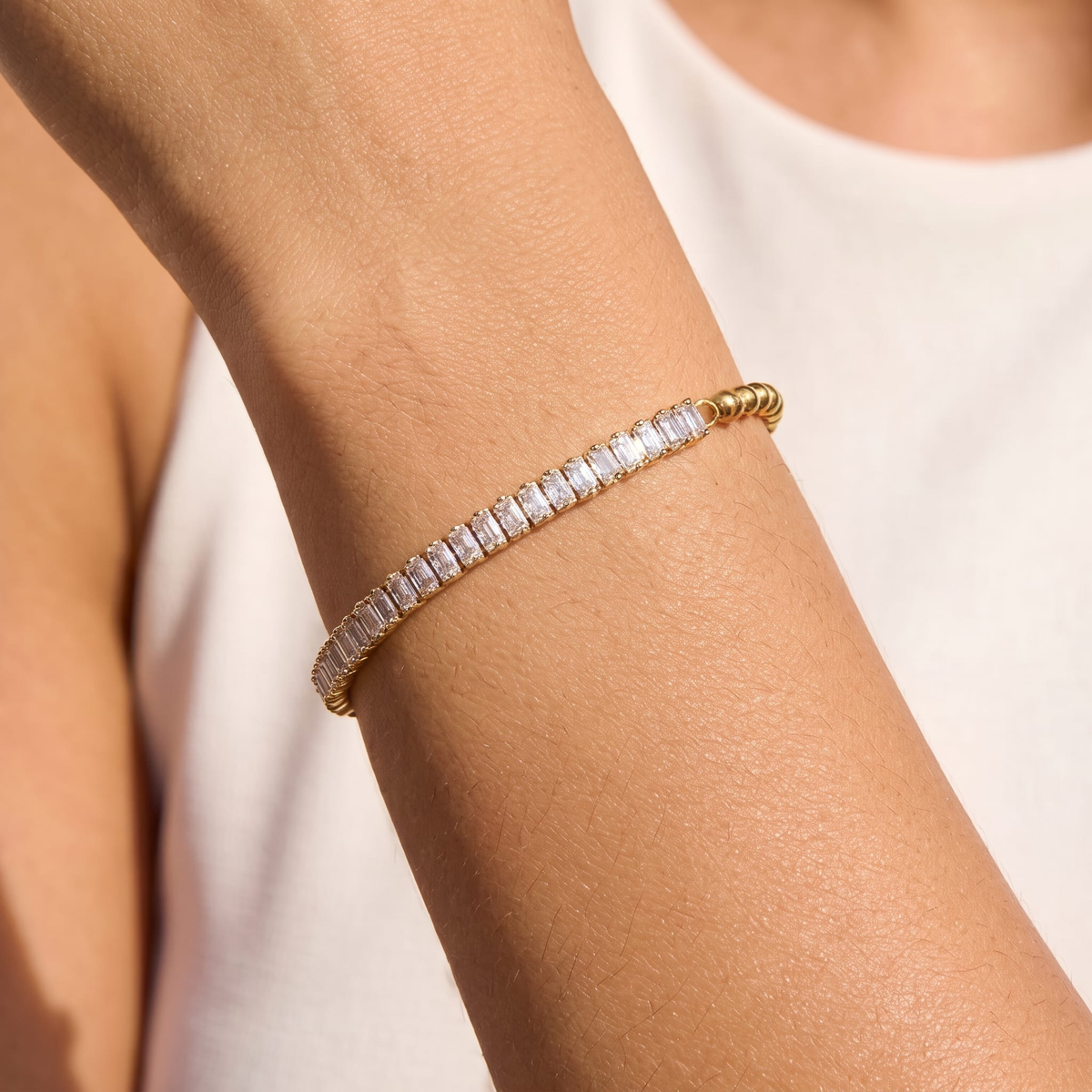 Woman wearing the Vida baguette bead gold bracelet on the wrist, featuring clear crystals