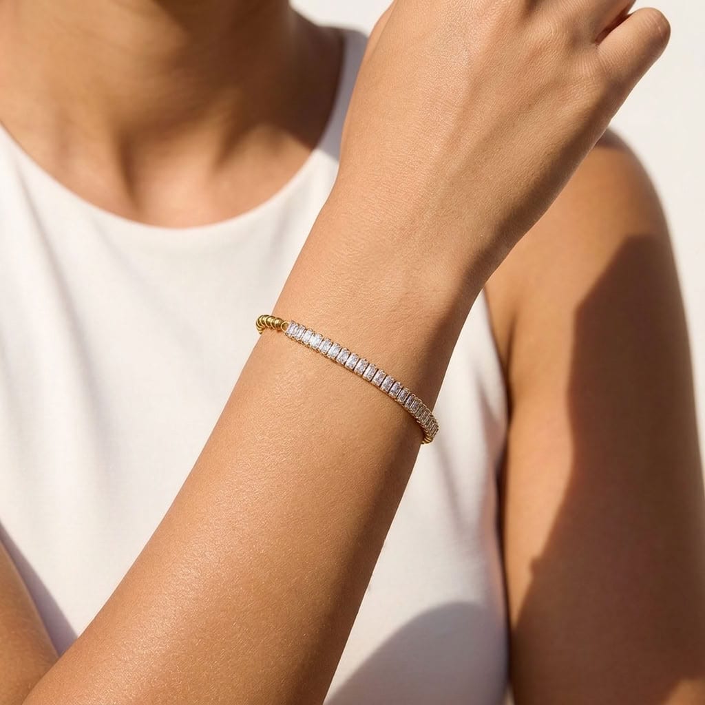 Wider view of a woman wearing the Vida baguette bead gold bracelet on the wrist, featuring clear crystals