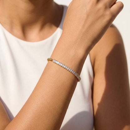 Wider view of a woman wearing the Vida baguette bead gold bracelet on the wrist, featuring clear crystals