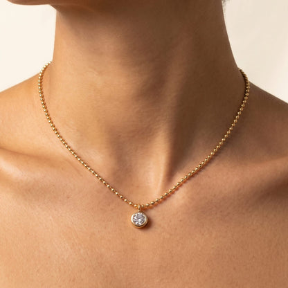 Close-up of a woman wearing the Vida crystal bezel gold necklace at the base of her neck