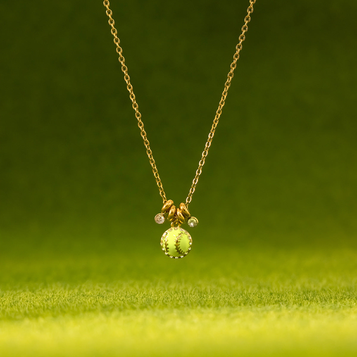Vida softball necklace suspended above bright green artificial turf