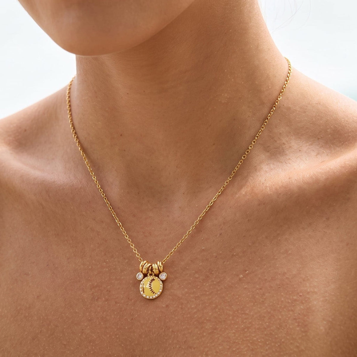 Woman wearing the Vida softball charm gold necklace at the collarbone