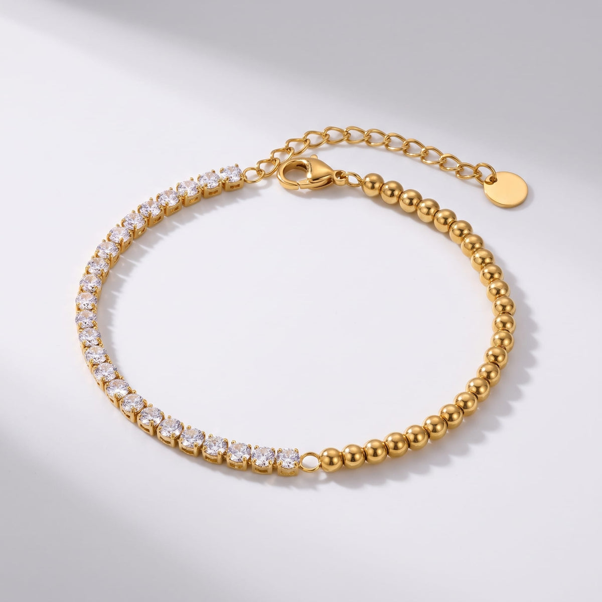Vida tennis bead gold bracelet on a plain white surface showing clasp and extension chain