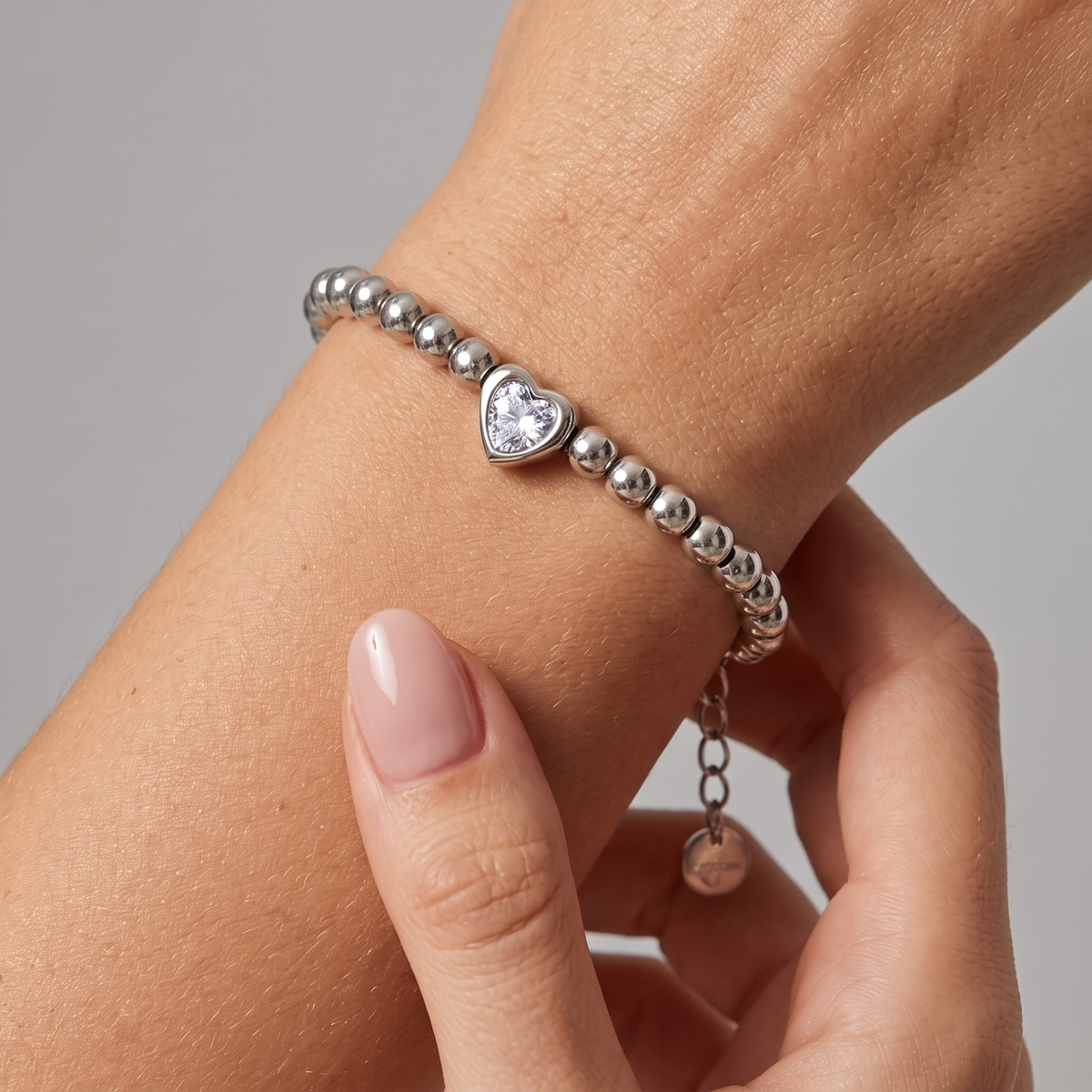 Woman wearing the Vittoria silver beaded bracelet with a heart-cut crystal and extender chain on the wrist