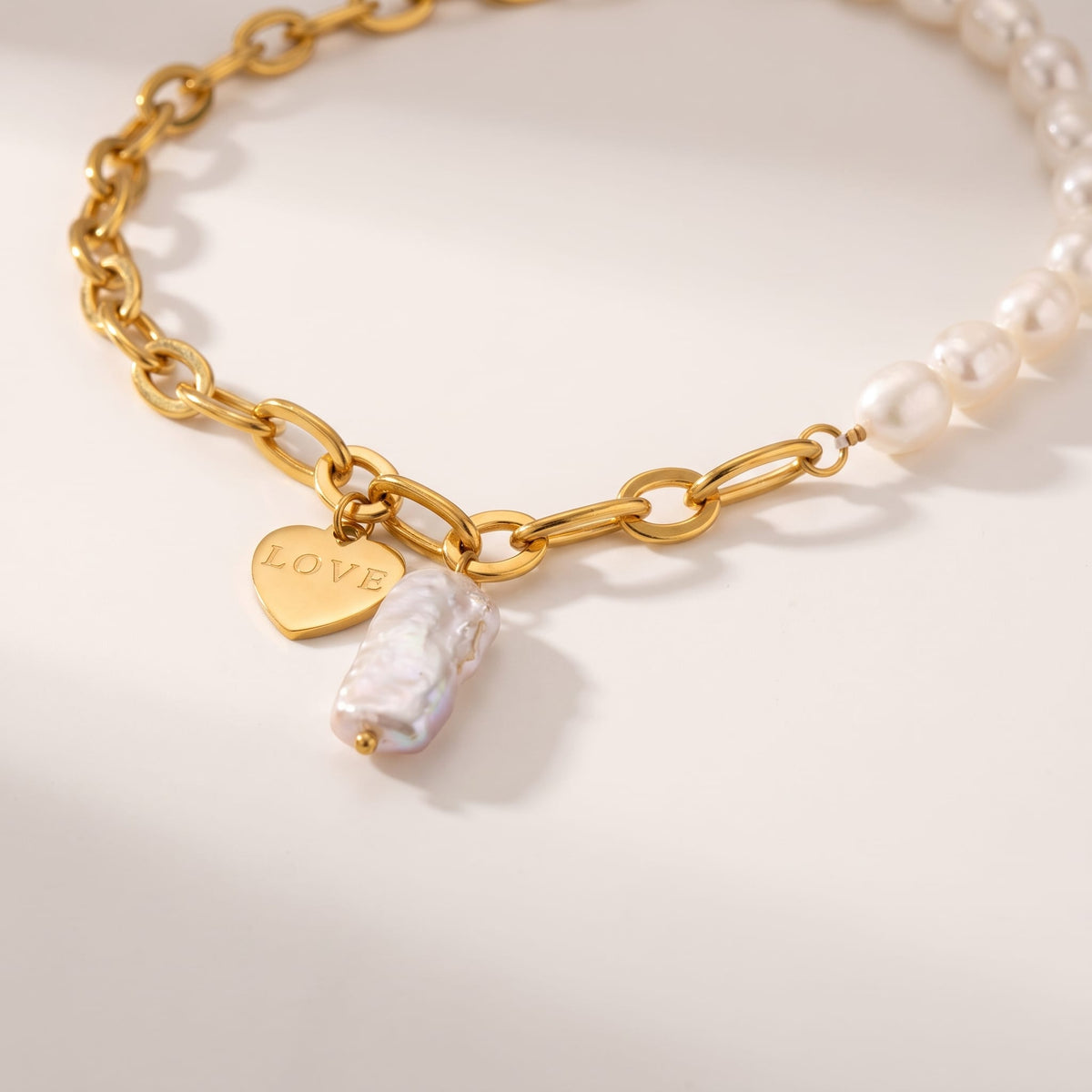 Vivienne pearl love gold necklace on a neutral background with soft shadows