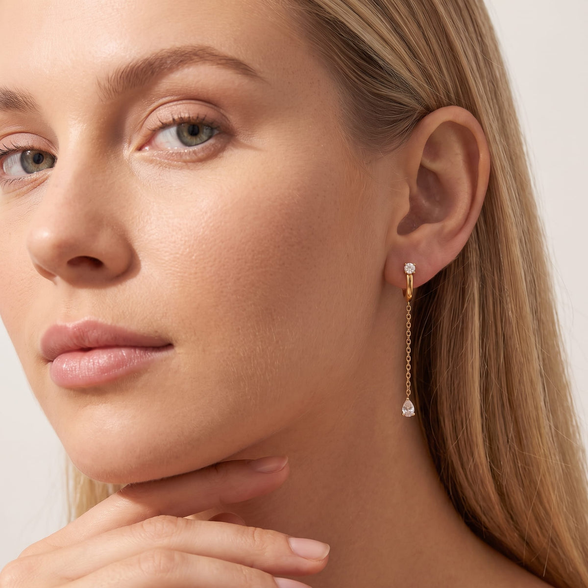 Woman wearing the Yvette chain drop gold earrings on the ear with hand under chin
